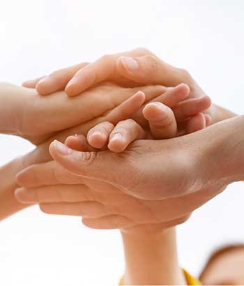 Group of people who are working together with their hands stacked on top of each other