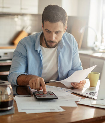 A man going over finances in front of a laptop and calculator