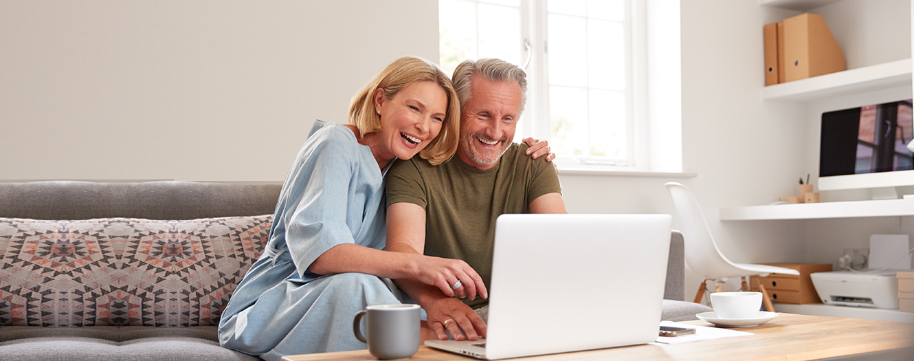 Happy middle aged couple looking at a laptop together