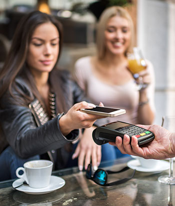 Ladies at a restaurant paying with a smartphone