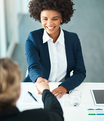 Two business women shaking hands in an office