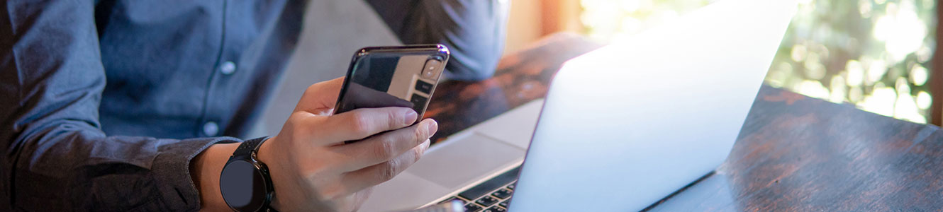 Man in office using a laptop computer and smartphone