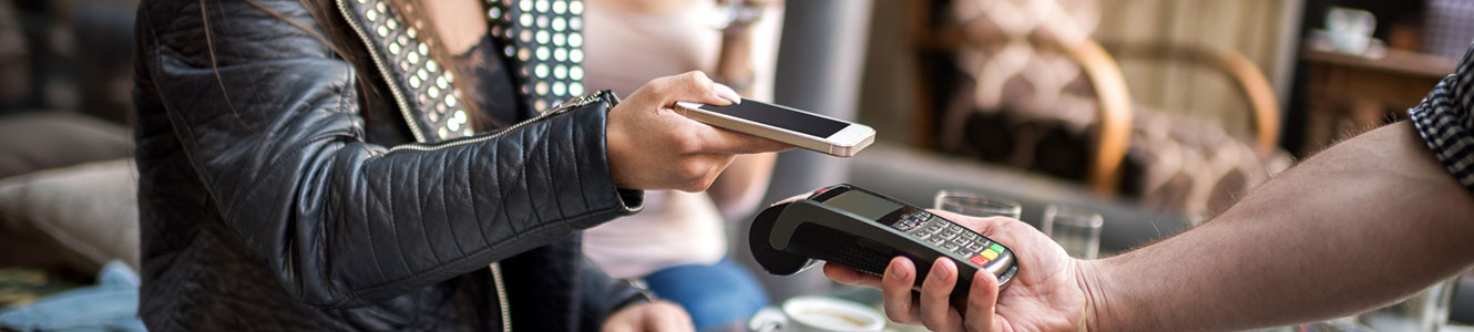 Lady in a restaurant paying with her phone at a credit card terminal