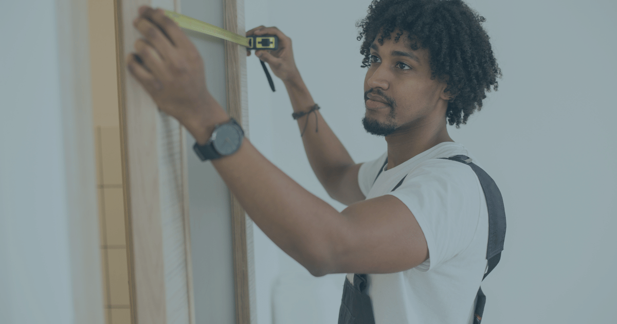 A  man measuring a door way with a measuring tape.